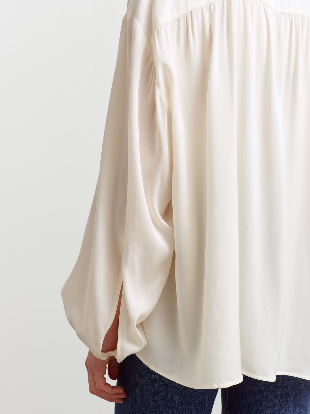 Caen blouse in cloud dancer silk blend, close-up of the fluid drape over denim