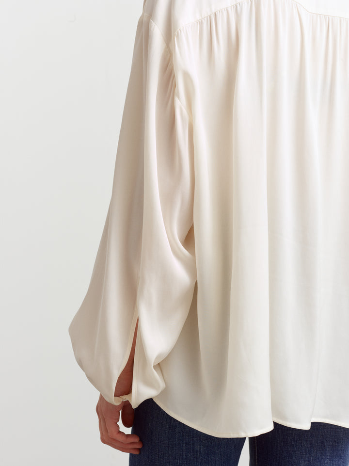 Caen blouse in cloud dancer silk blend, close-up of the fluid drape over denim