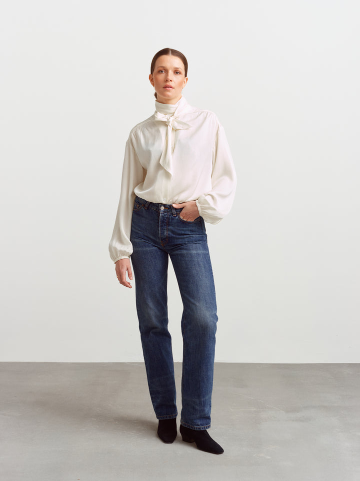 Caen blouse in cloud dancer silk blend, neck scarf tied at the collar, worn with blue jeans