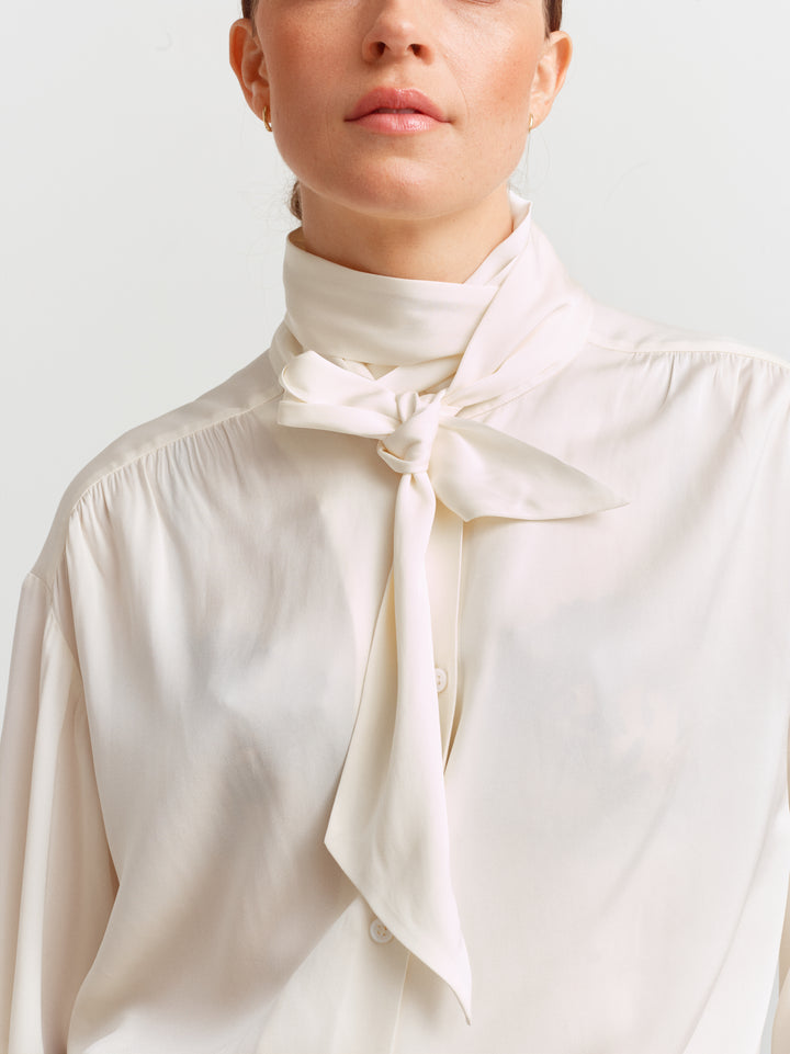 Caen blouse in cloud dancer silk blend, close-up of the detachable neck scarf tied at the throat
