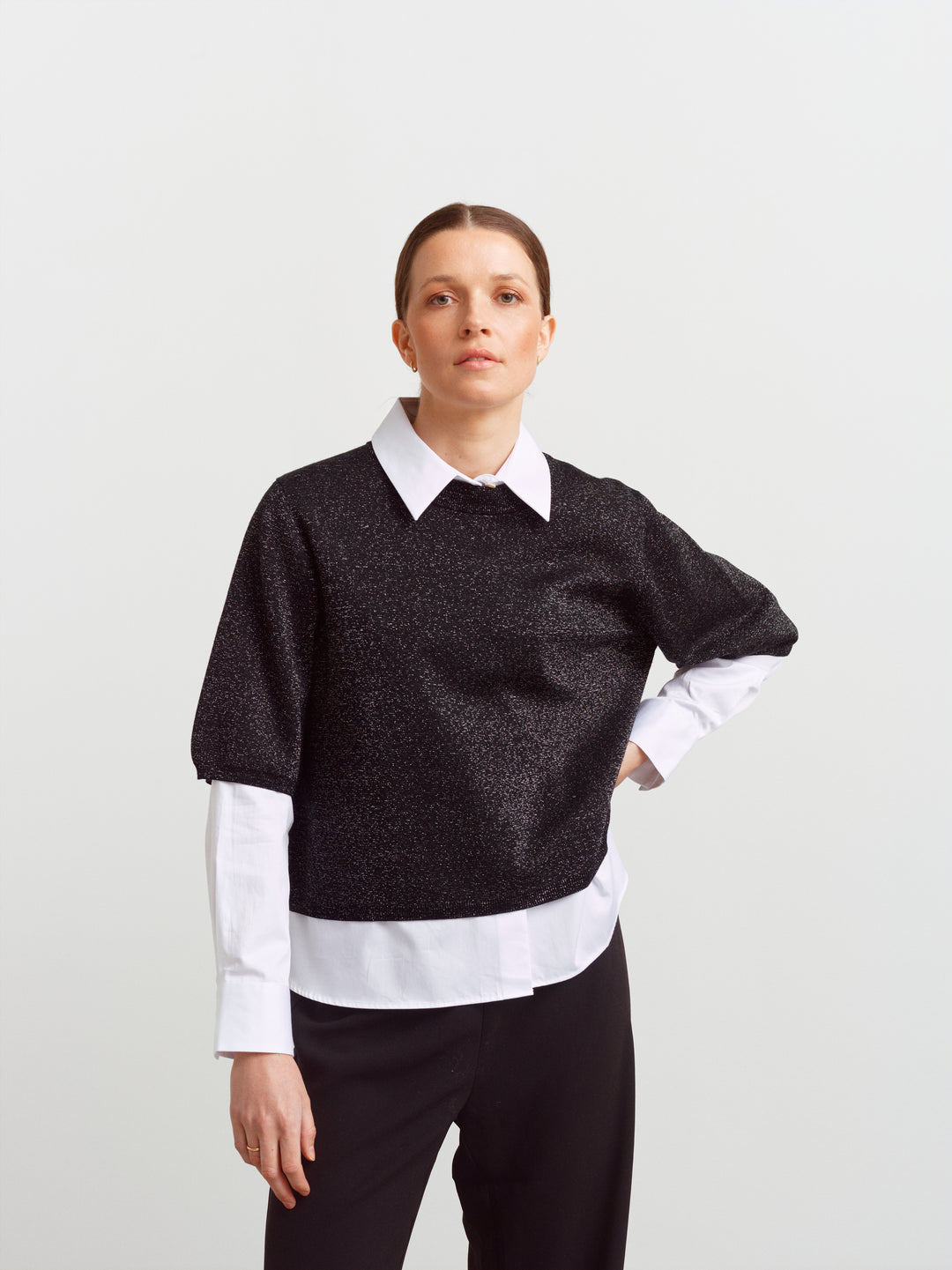 Modena tee in black glow, worn over a crisp white shirt with sleeves showing beneath