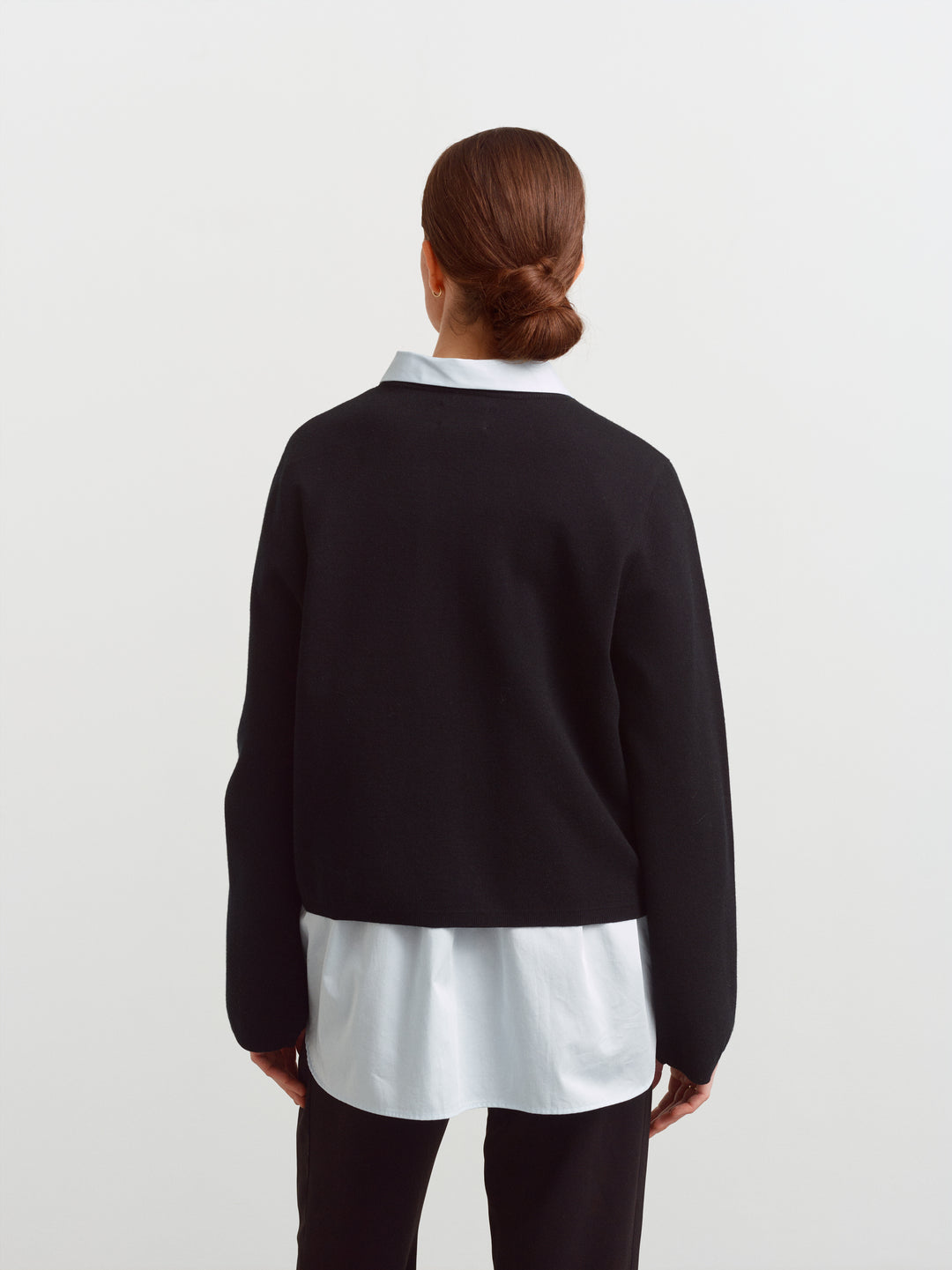 Montreal sweater in black merino wool, back view with shirt hem visible below the knit