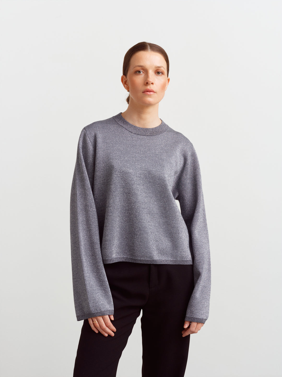 Montreal sweater in gun metal glow lurex knit, front view with straight fit over black trousers