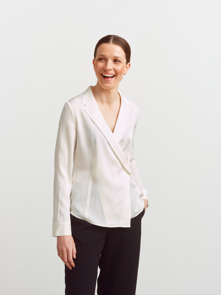 New York blouse in cloud dancer silk blend, full figure smiling with hands in trouser pockets