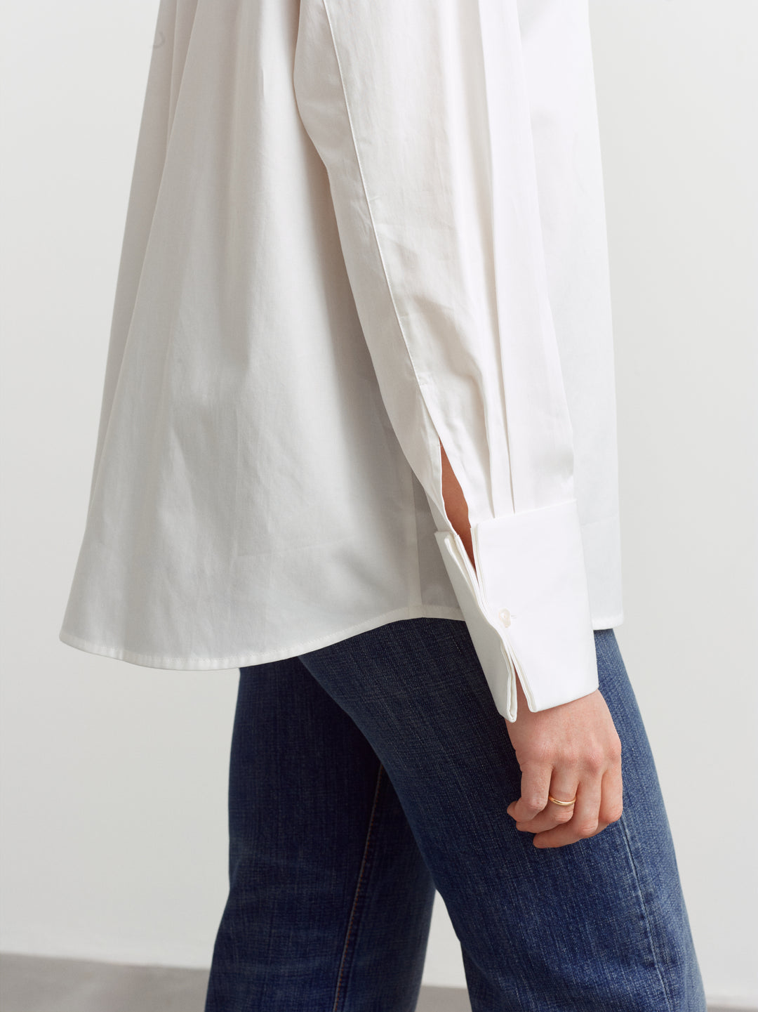 Odense shirt in white organic cotton, detail of wide buttoned cuff falling over blue denim