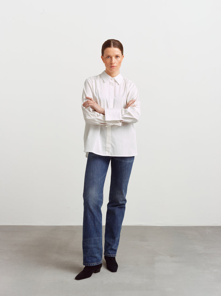 Odense shirt in white organic cotton, relaxed fit with arms crossed, worn with blue jeans