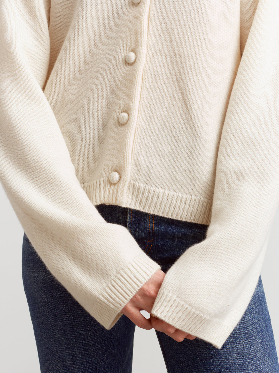 Verona cardigan in cloud dancer, close-up of ribbed cuffs and buttons worn over jeans